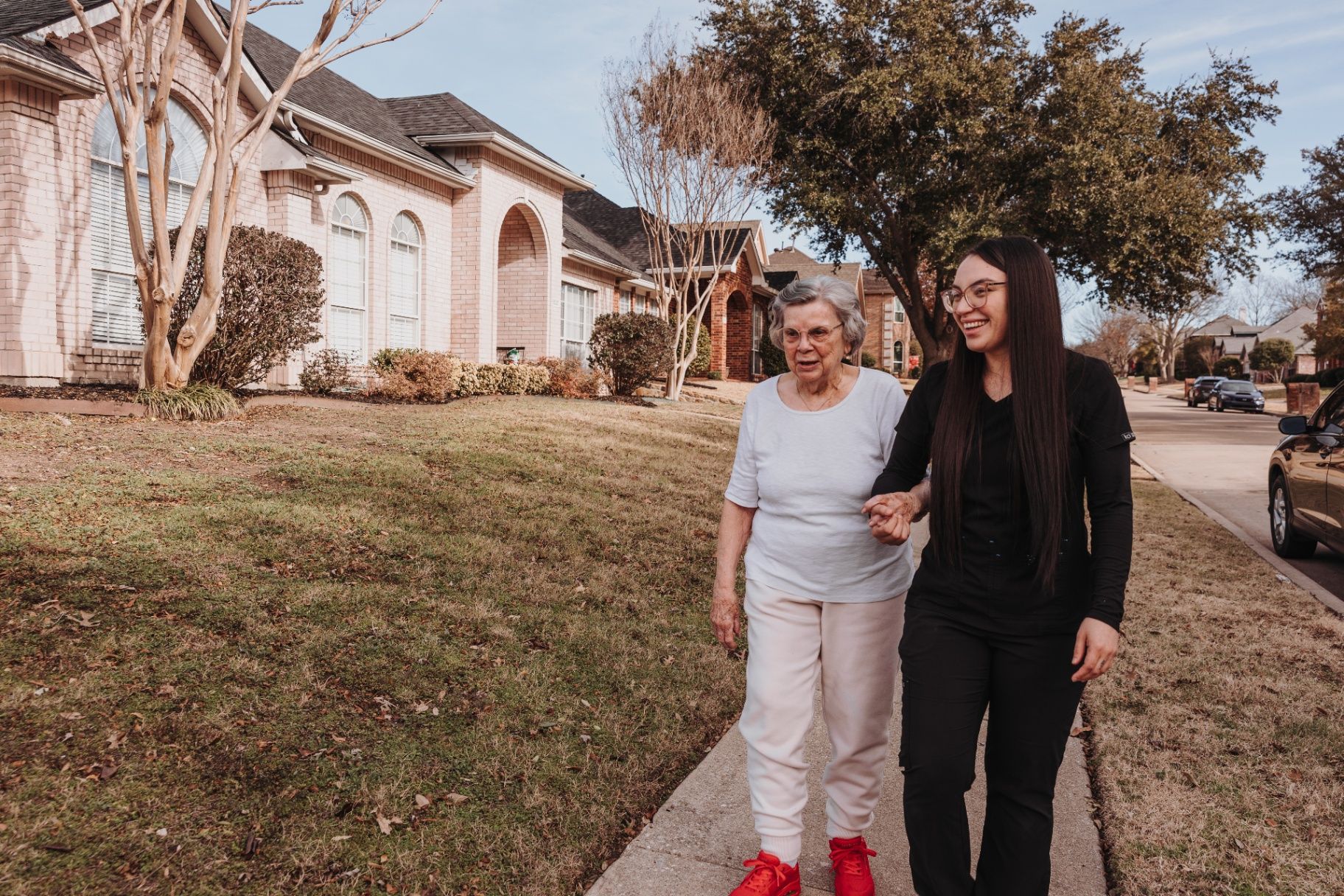 A caregiver and resident walking beside the community
